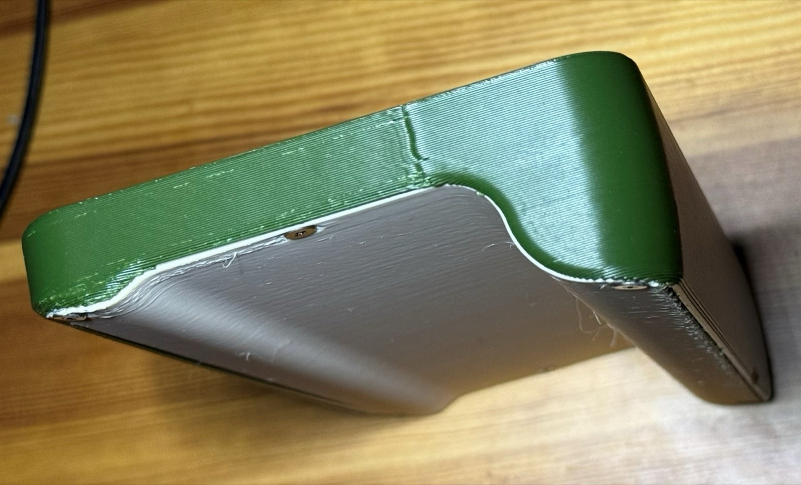 Underside of the green two-piece shell showing the battery bulge and the join line