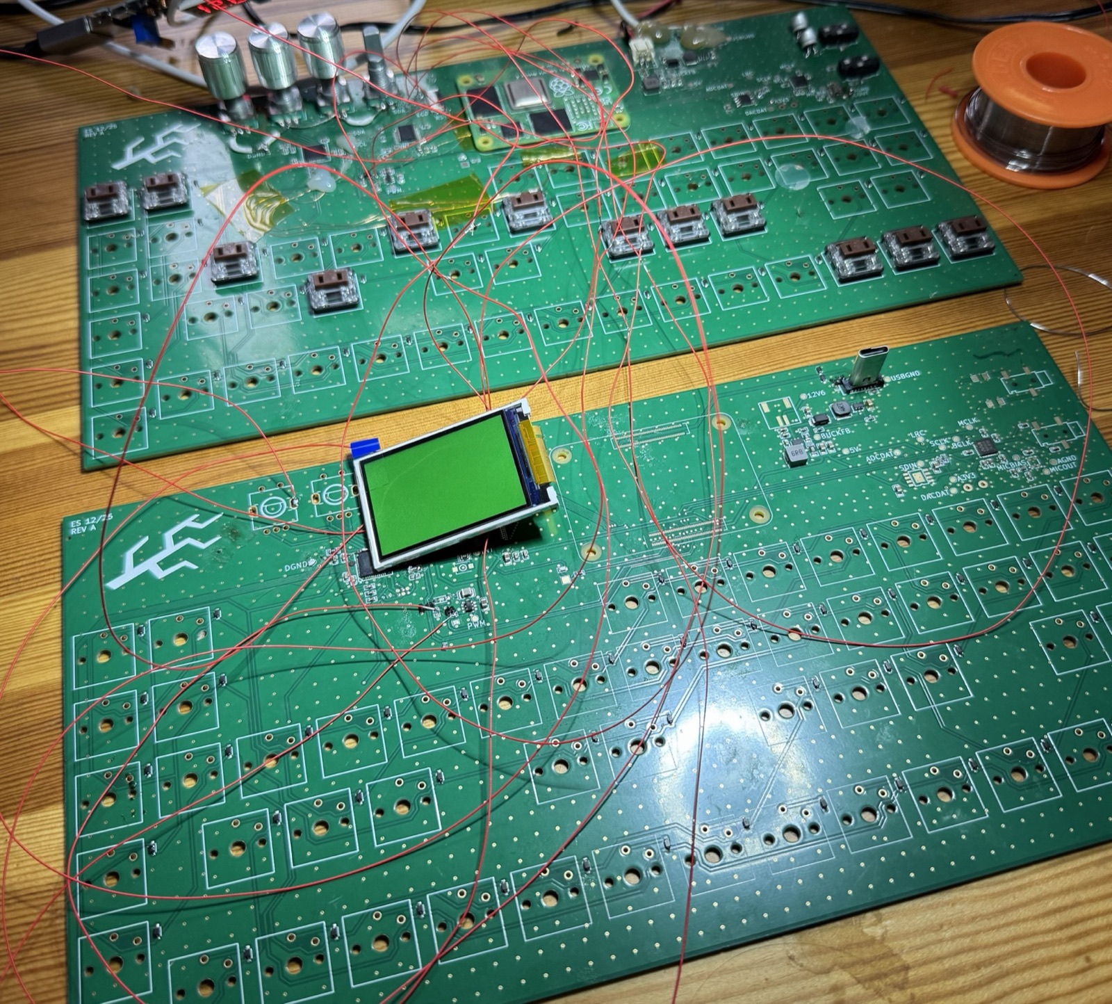 Two green circuit boards side by side, joined by dozens of thin red wires, with an LCD lit up green on the second board